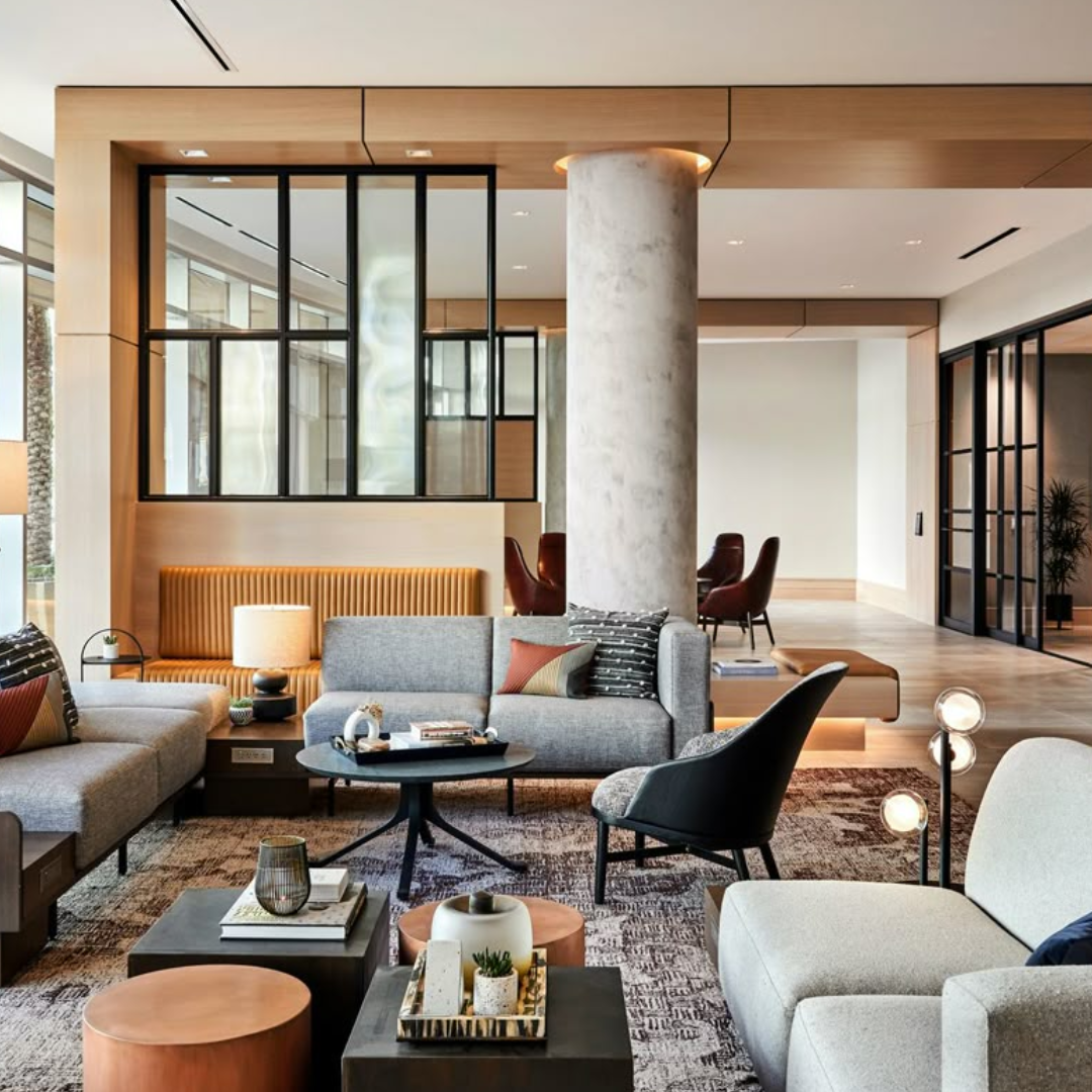Area lounge contract con arredi contemporanei e pareti vetrate Ampia area lounge contract con divani e poltrone in tonalità neutre e terracotta, tavolini bassi, pareti vetrate e finiture in legno.
